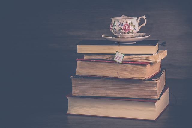 Stack of worn books with a tea cup on top.